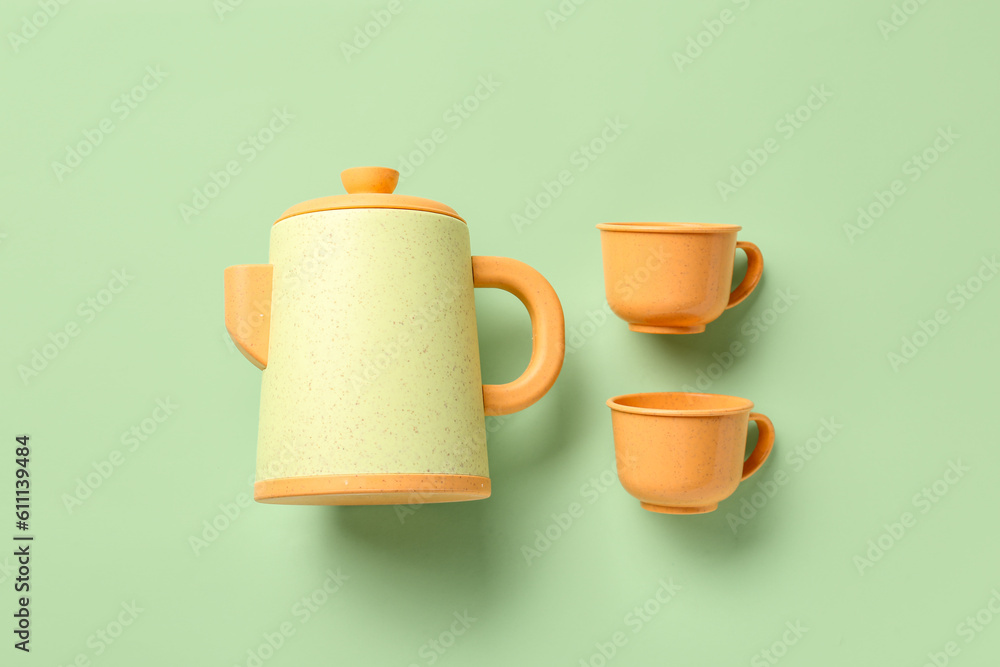 Teapot with cups for baby on pale green background