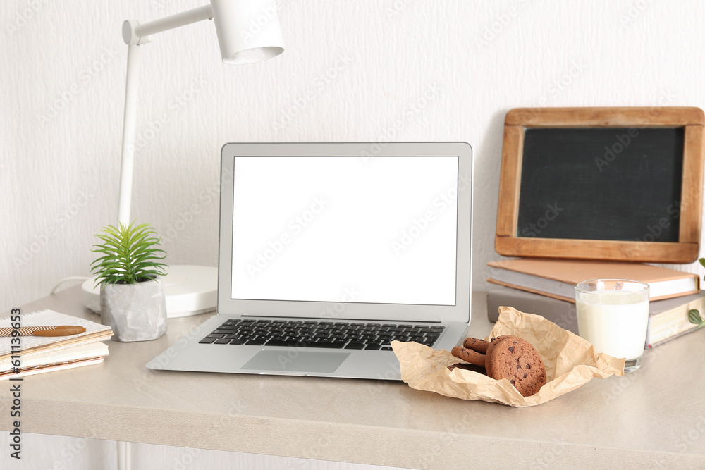 Cookies with glass of milk and laptop on table in room