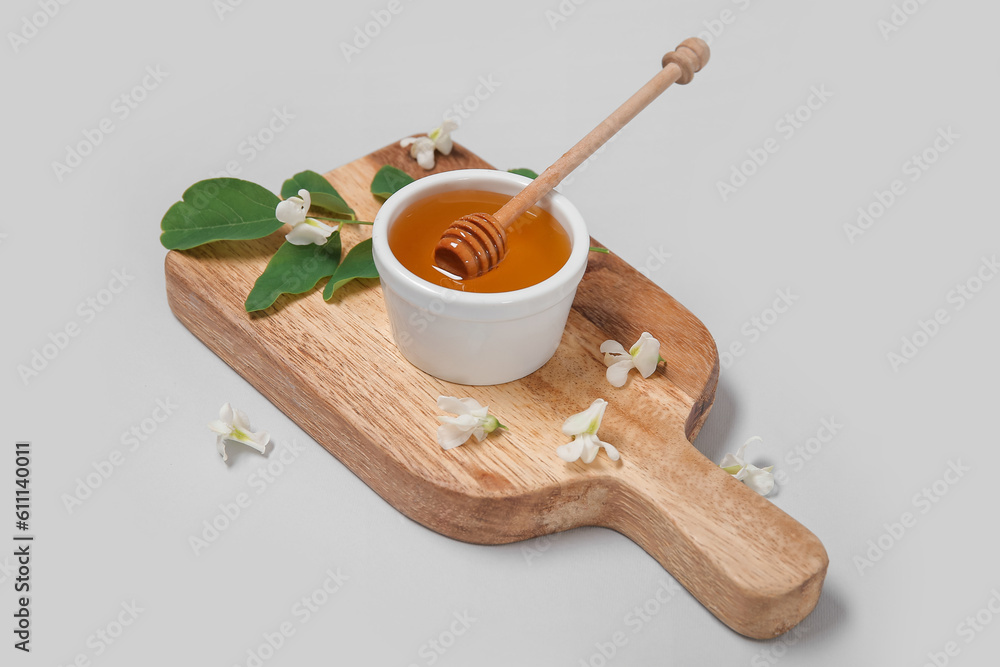 Bowl of honey with flowers of acacia and branch on white background