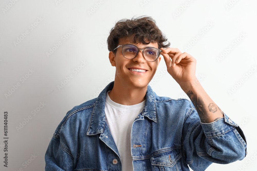 Young man in stylish eyeglasses on light background