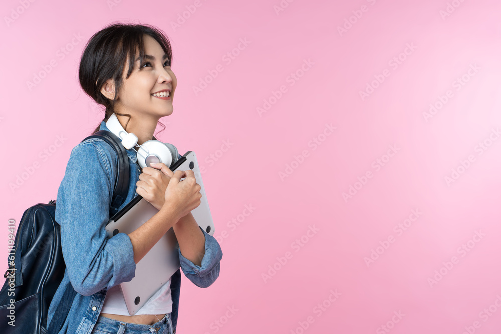 Portrait of smiling young Asian college student look to the side of the empty space with laptop and 