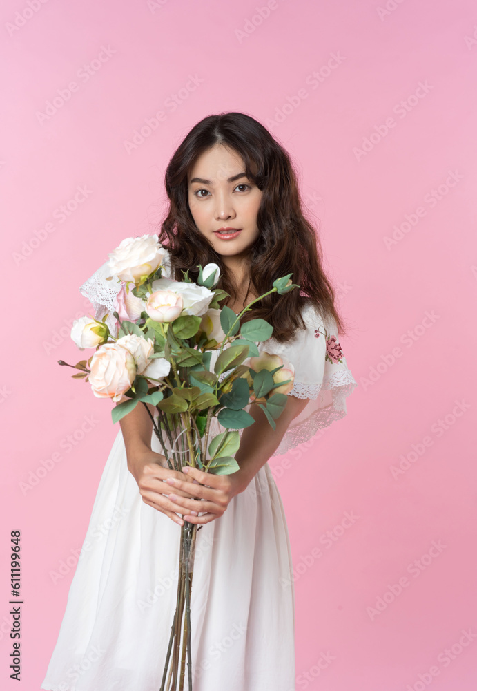 Young Asian woman holding a rose bouquet on hand isolated pink color background