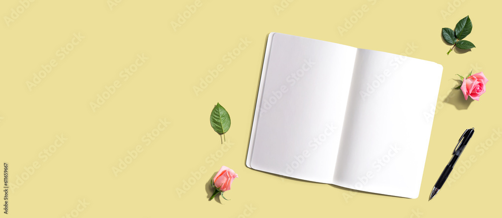 Open notebook or diary with a pen from above with rose buds- flat lay