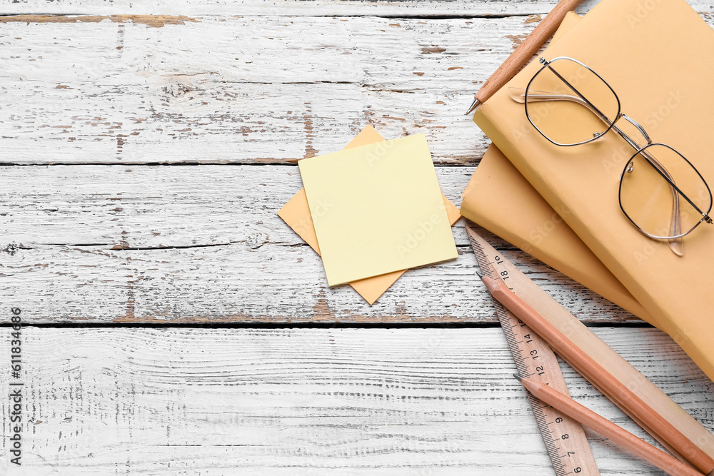 Sticky notes with stationery and eyeglasses on white wooden background. Update concept