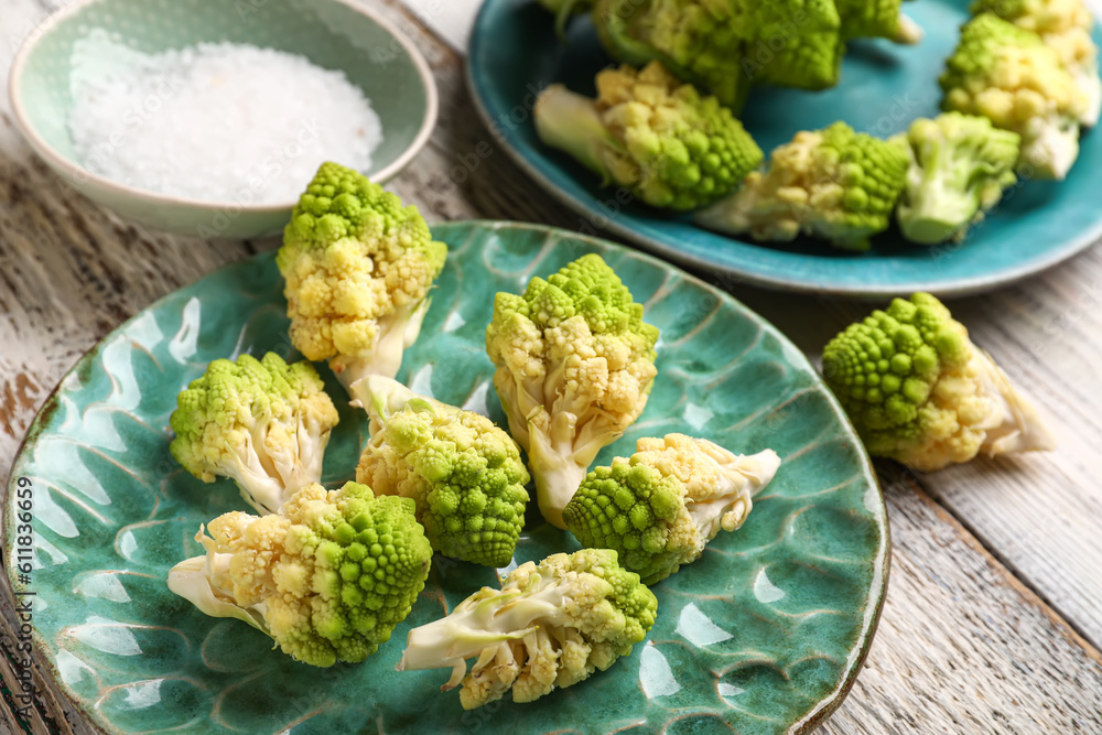 Plate with romanesco cabbage on light wooden background