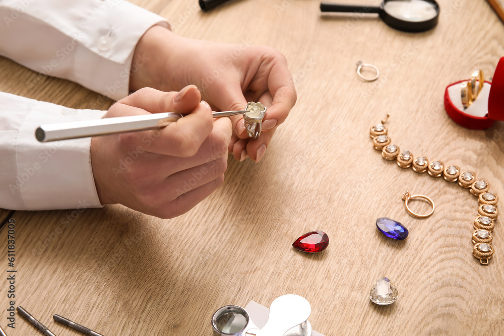 Female jeweler making ring on wooden table, closeup