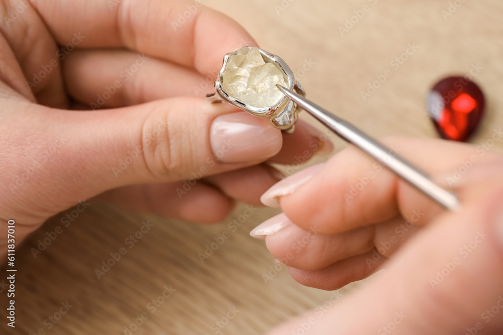 Female jeweler making ring on wooden table, closeup