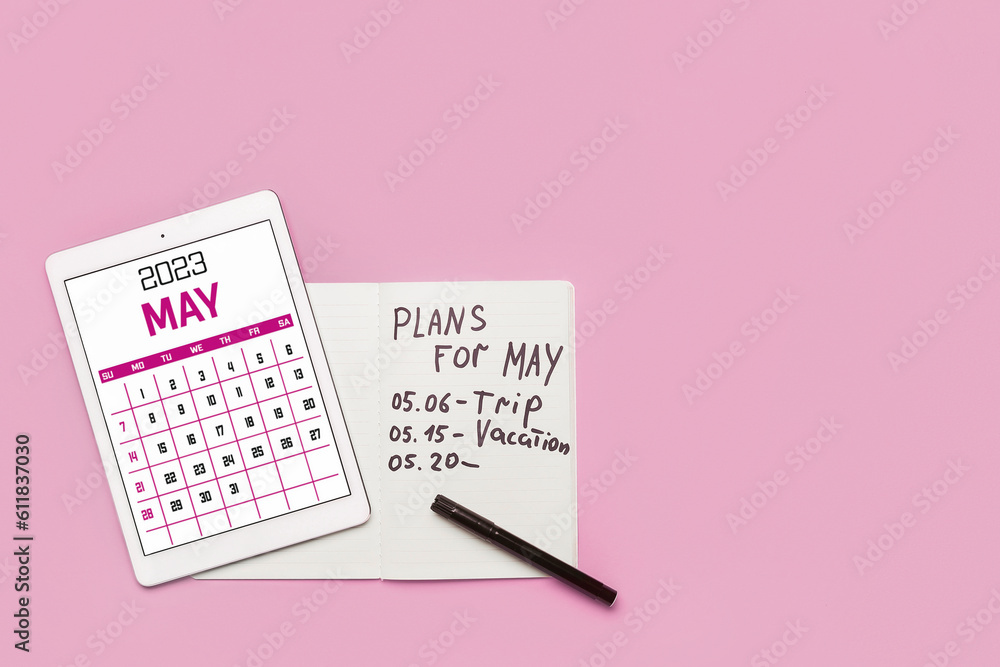 Modern tablet computer with calendar and notebook with plans for May on pink background