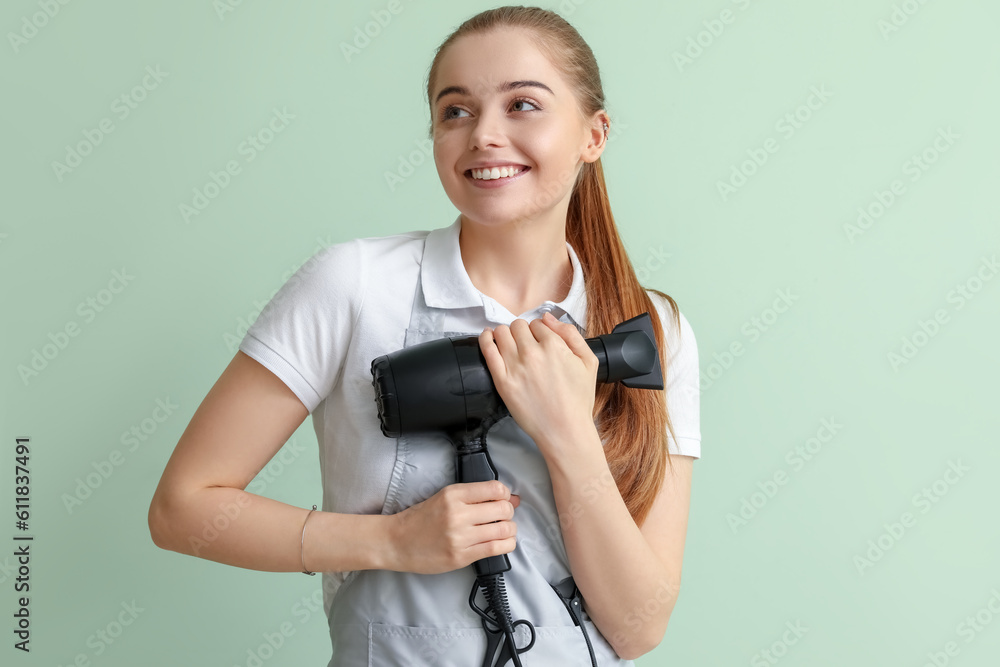 Female hairdresser with dryer on green background