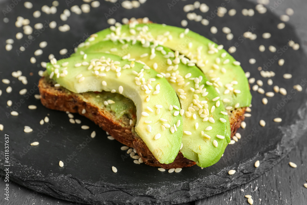 Slate board of tasty avocado toast on table, closeup