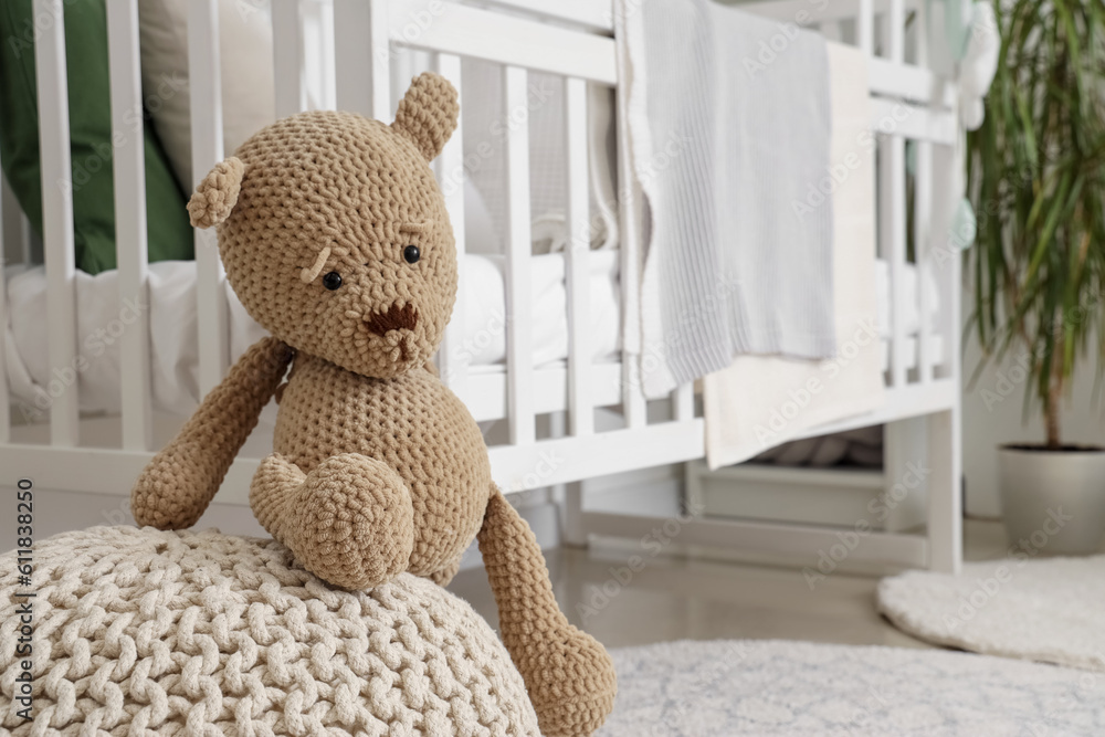 Cute teddy bear on ottoman in childrens room