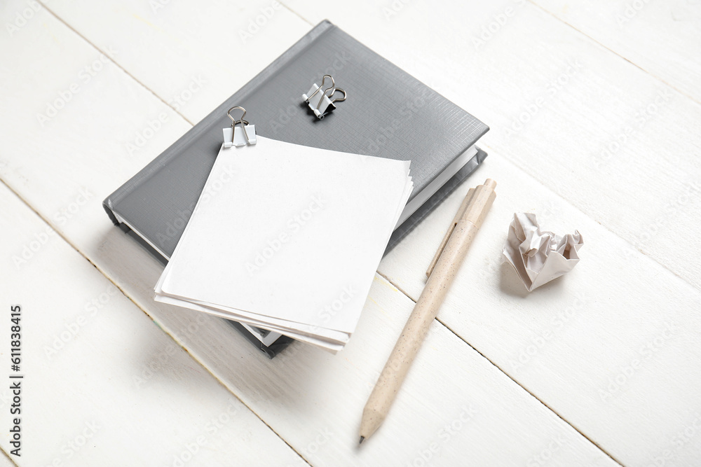 Sticky notes with different stationery supplies on white wooden background