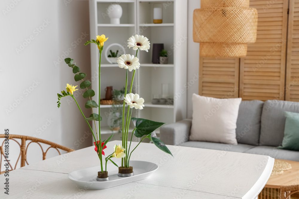 Beautiful ikebana on dining table in room