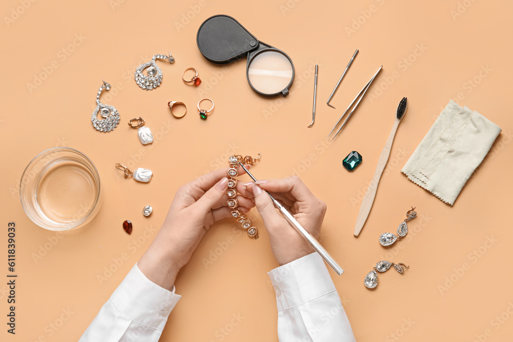 Woman cleaning beautiful accessories on color background