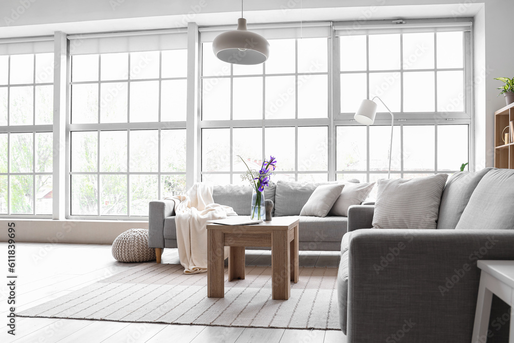 Interior of light living room with grey sofas and big window