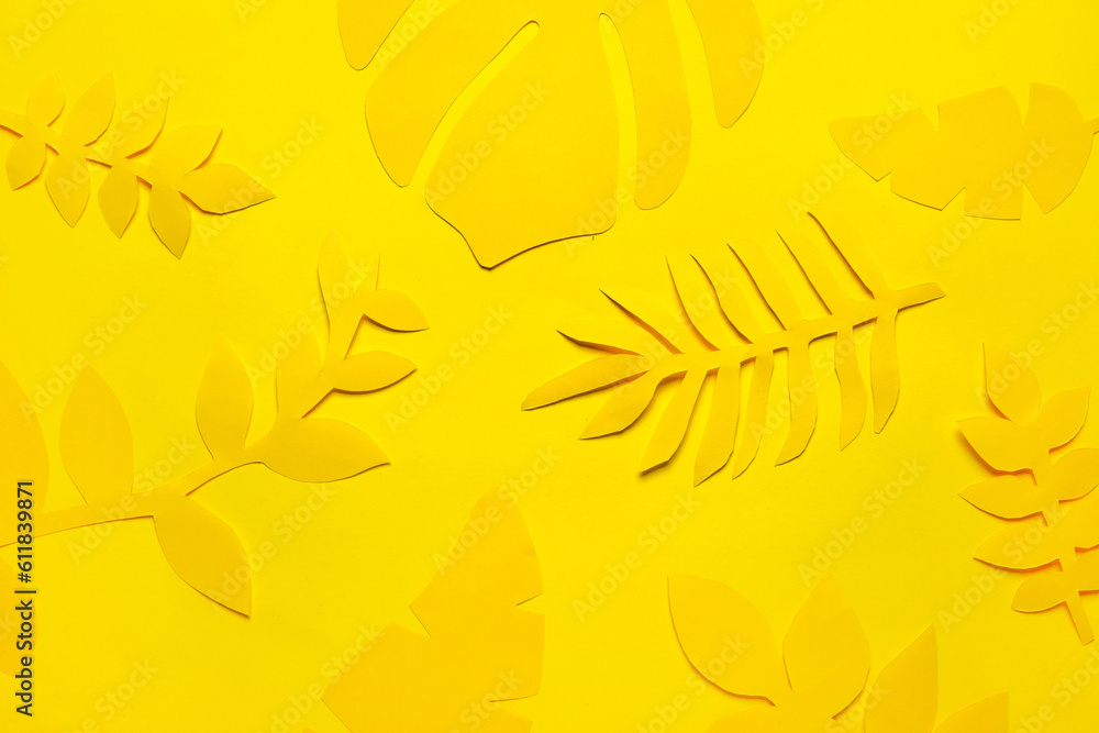 Different paper tropical leaves on yellow background