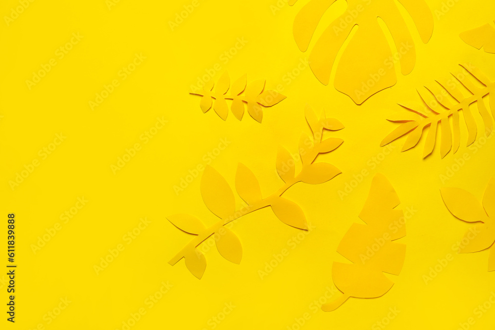 Different paper tropical leaves on yellow background