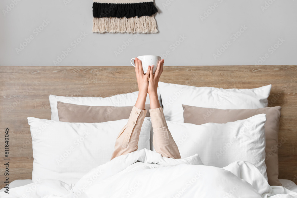 Morning of young woman with cup of coffee in bed