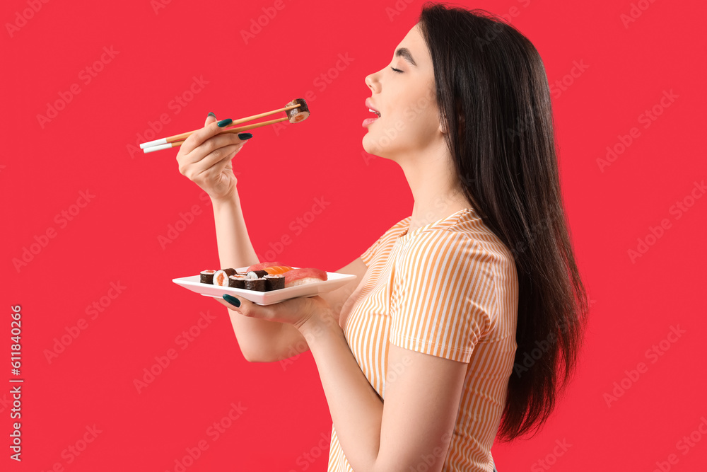 Young woman eating sushi rolls on red background