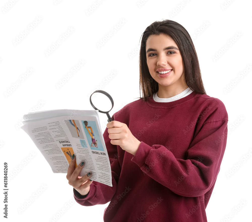 Young woman with magnifier reading newspaper on white background