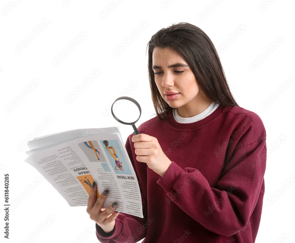 Young woman with magnifier reading newspaper on white background