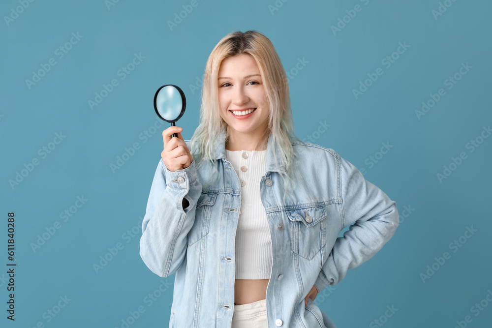 Young woman with magnifier on blue background