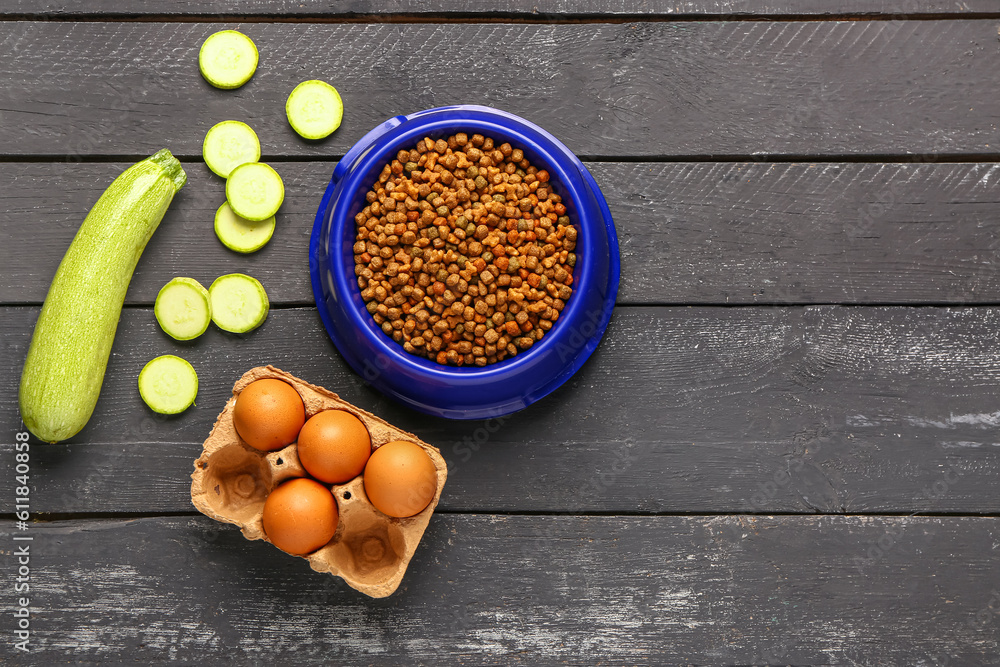 Bowl with dry pet food and natural products on dark wooden background