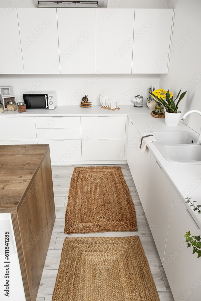 Wicker rugs on floor in interior of light kitchen