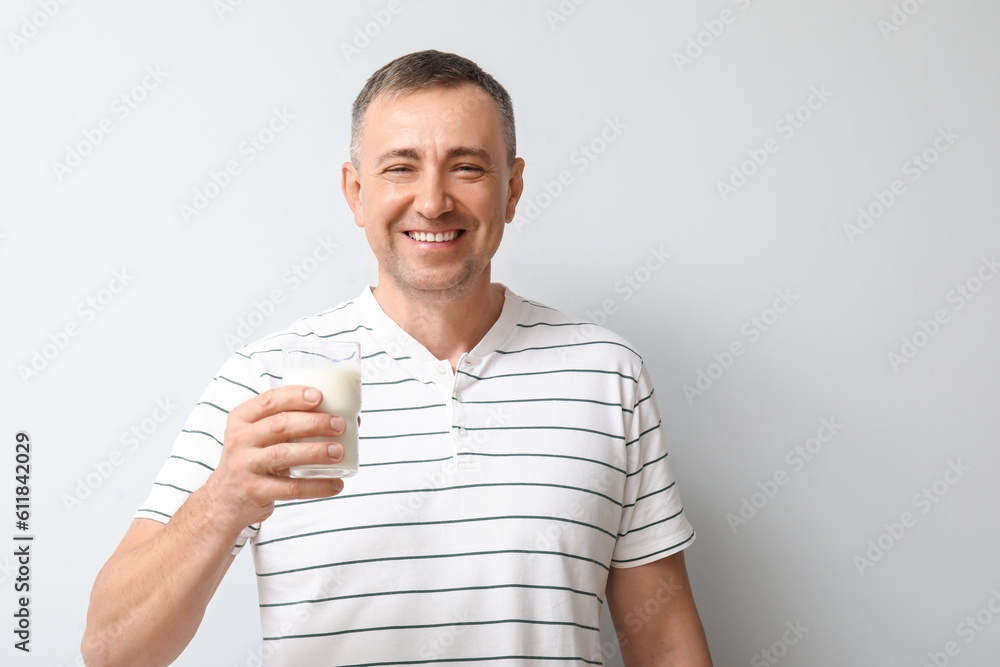 Mature man with glass of milk on white background