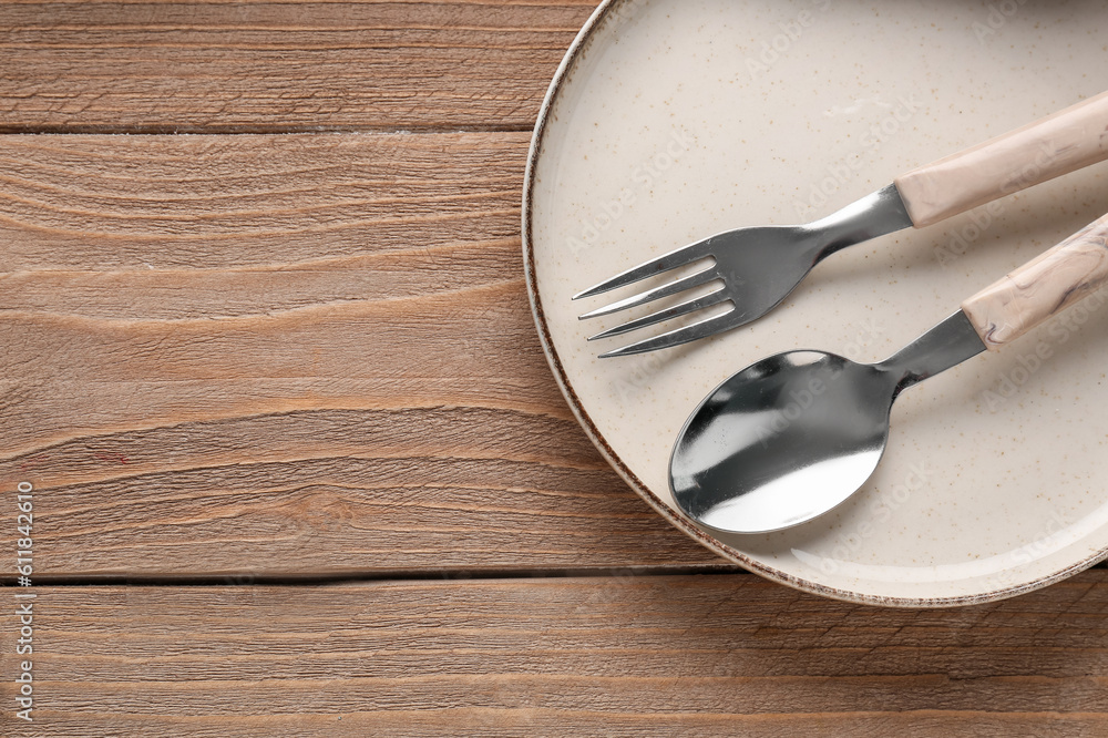 Silver spoon with fork and plate on wooden background