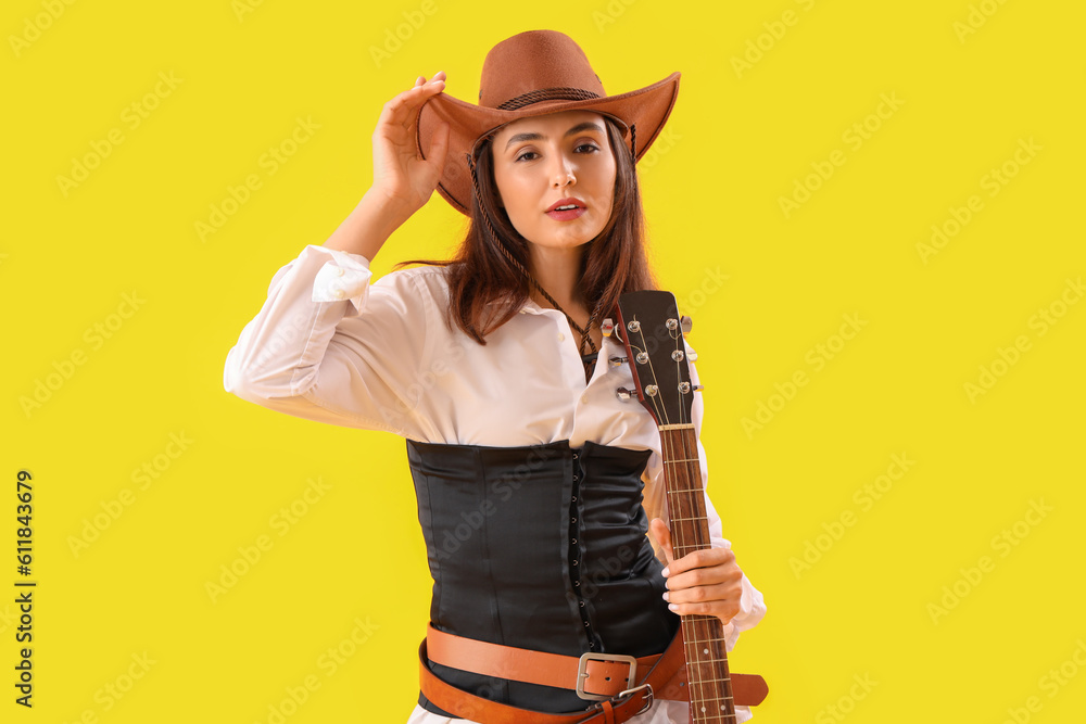 Beautiful cowgirl with guitar on yellow background