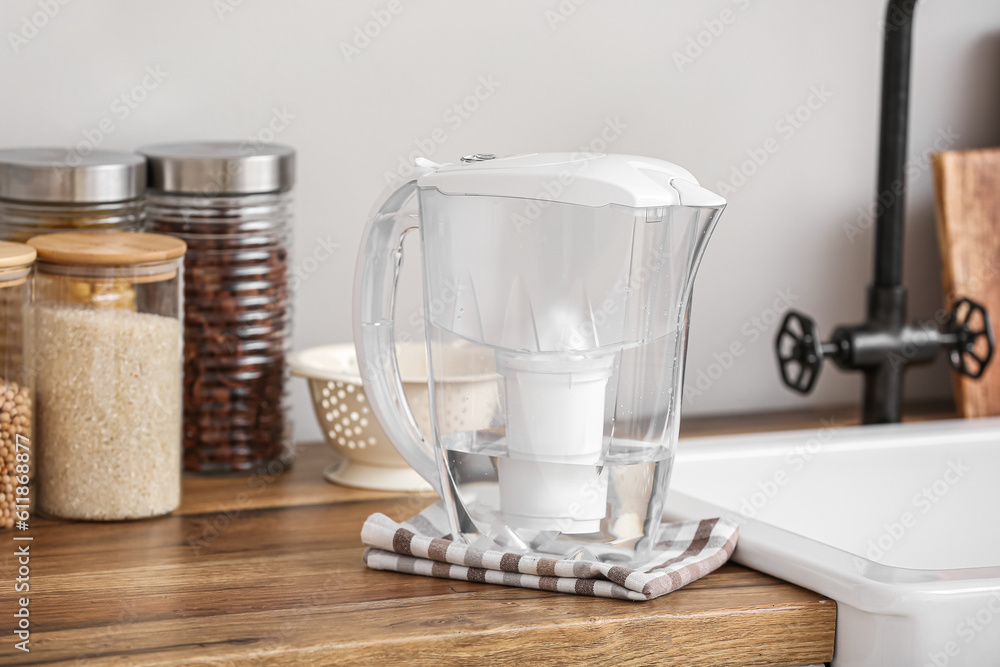 Water filter jug with napkin on kitchen counter near light wall