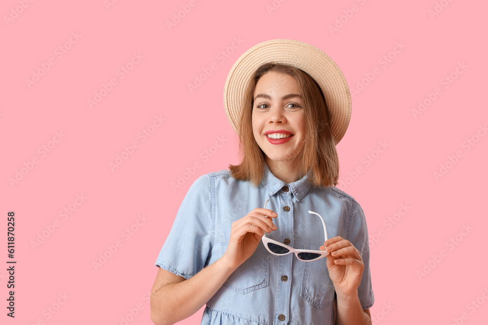 Young woman in hat with sunglasses on pink background