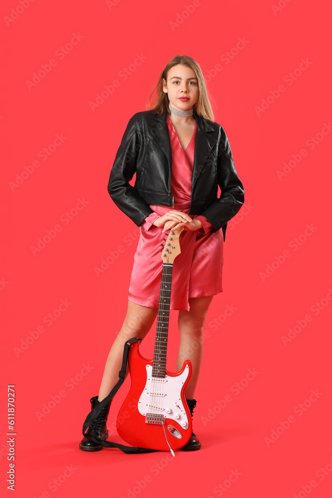 Young woman with guitar on red background