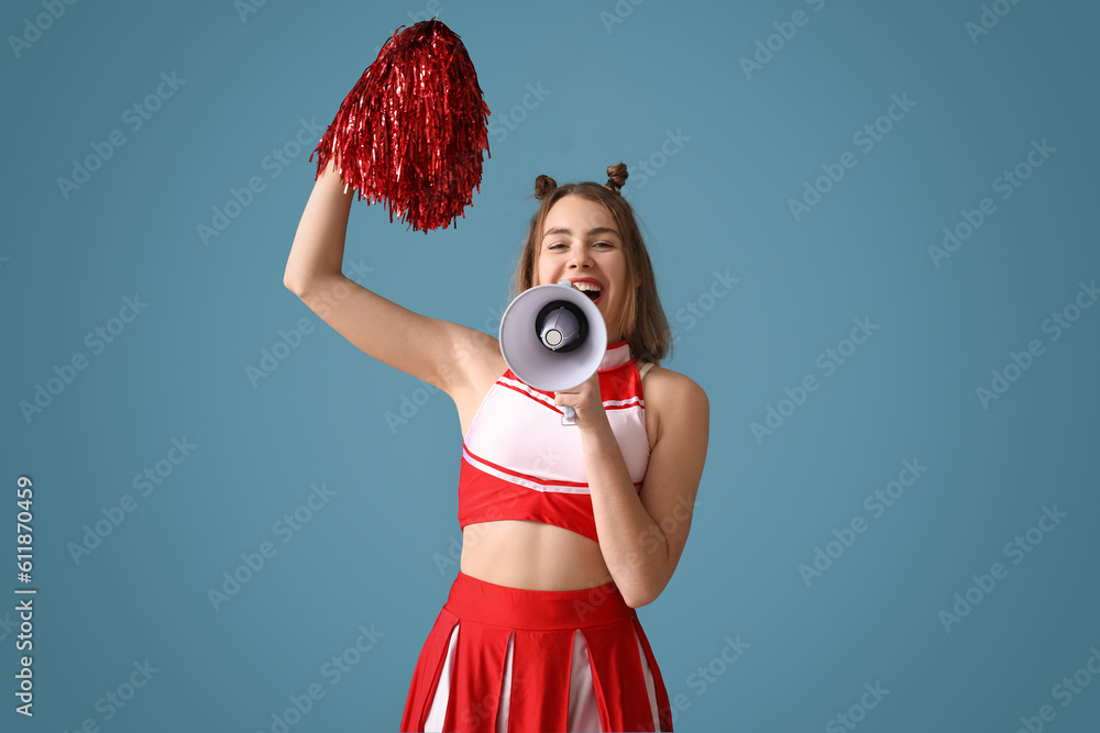 Beautiful cheerleader shouting into megaphone on blue background