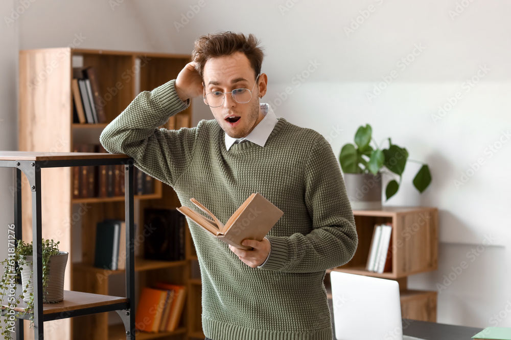 Shocked young man reading book in library