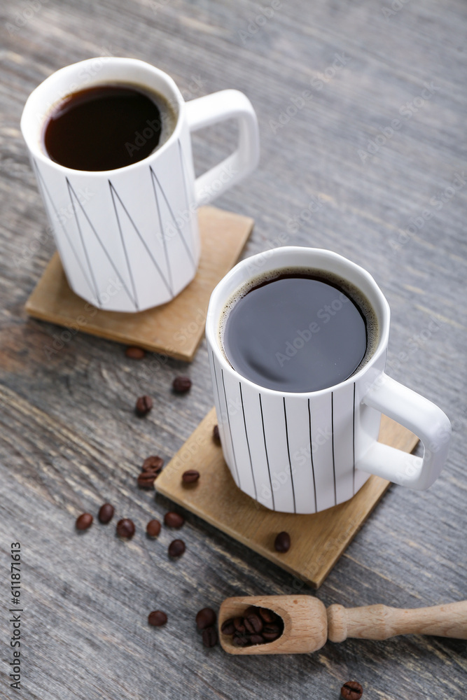 Drink coasters with cups of coffee and beans on wooden table