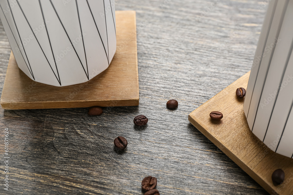 Drink coasters with cups and coffee beans on wooden table