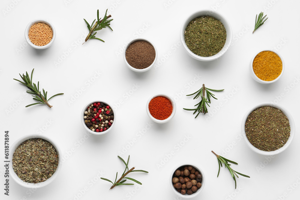 Composition with bowls of different spices and rosemary on light background