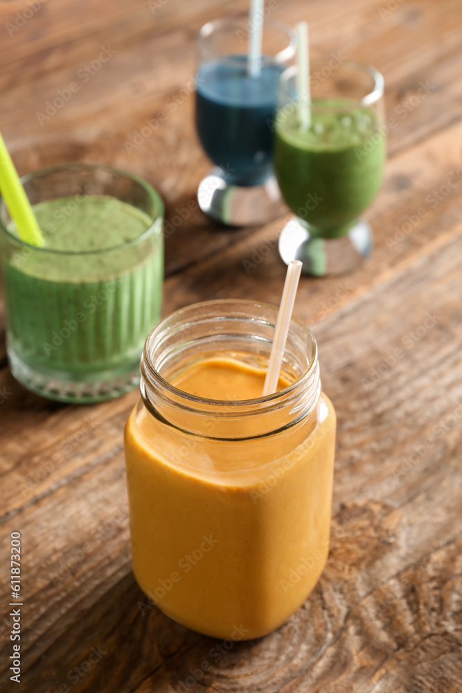 Mason jar of yellow smoothie on wooden background