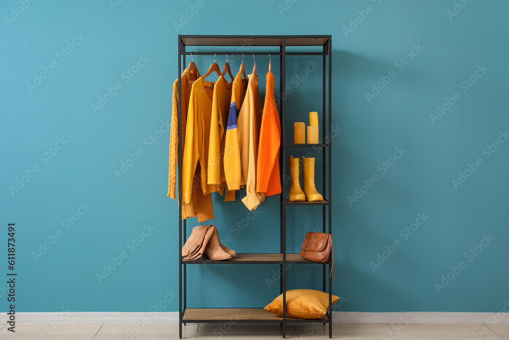 Shelving unit with clothes and shoes near blue wall