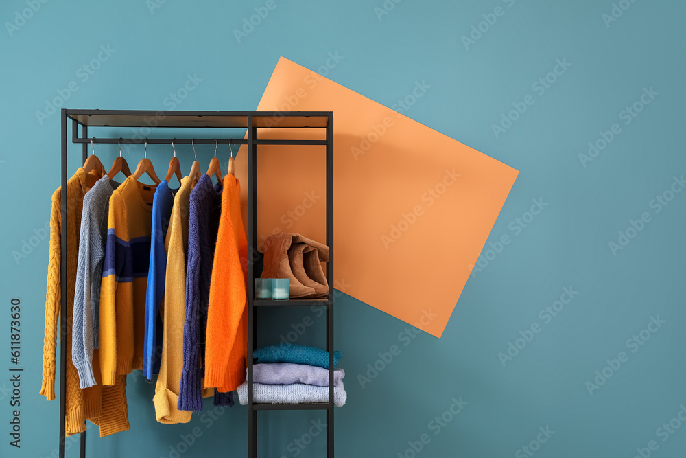 Shelving unit with clothes and shoes near blue wall