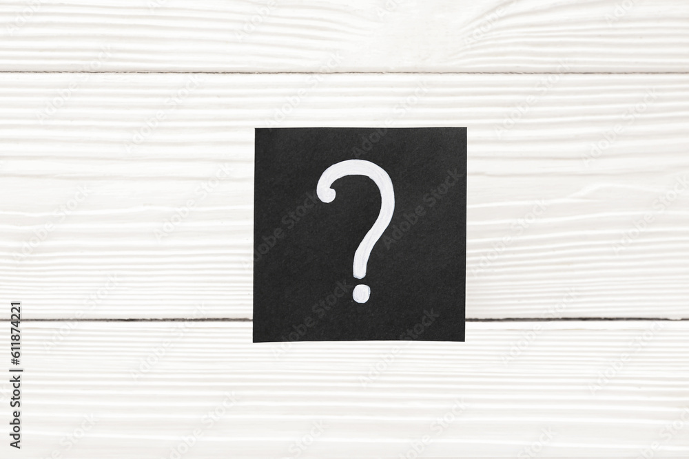 Paper with question mark on white wooden background