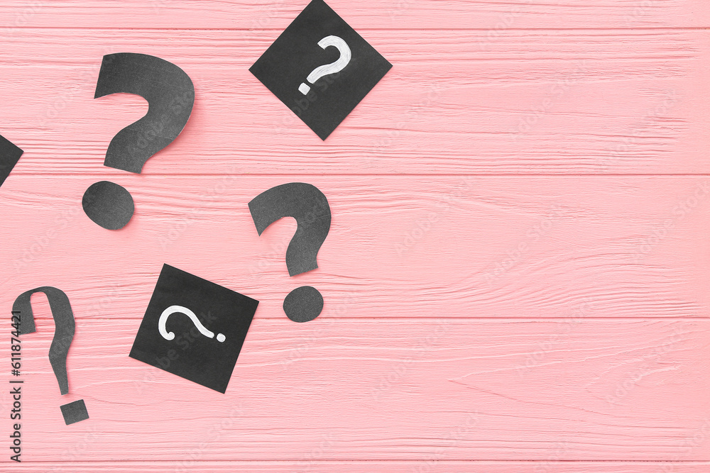 Paper question marks on pink wooden background