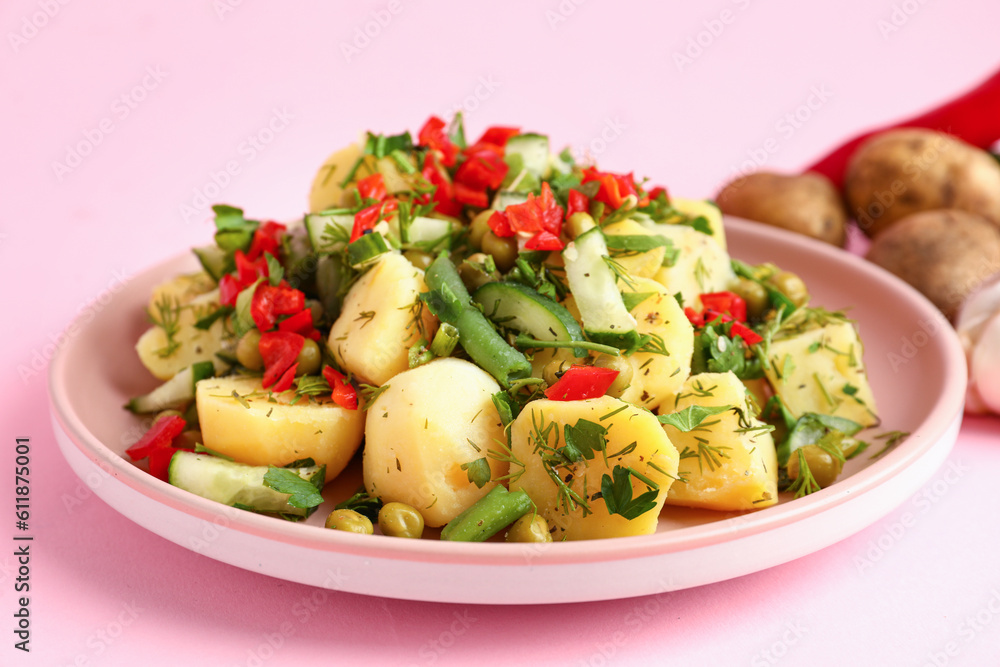 Plate of tasty Potato Salad with vegetables on pink background