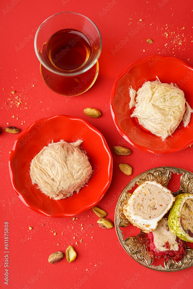 Tasty Turkish Pismaniye, delight and glass of tea on red background