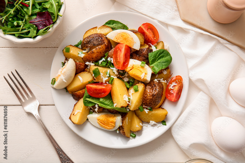 Plate of tasty potato salad with eggs and tomatoes on light wooden background, top view