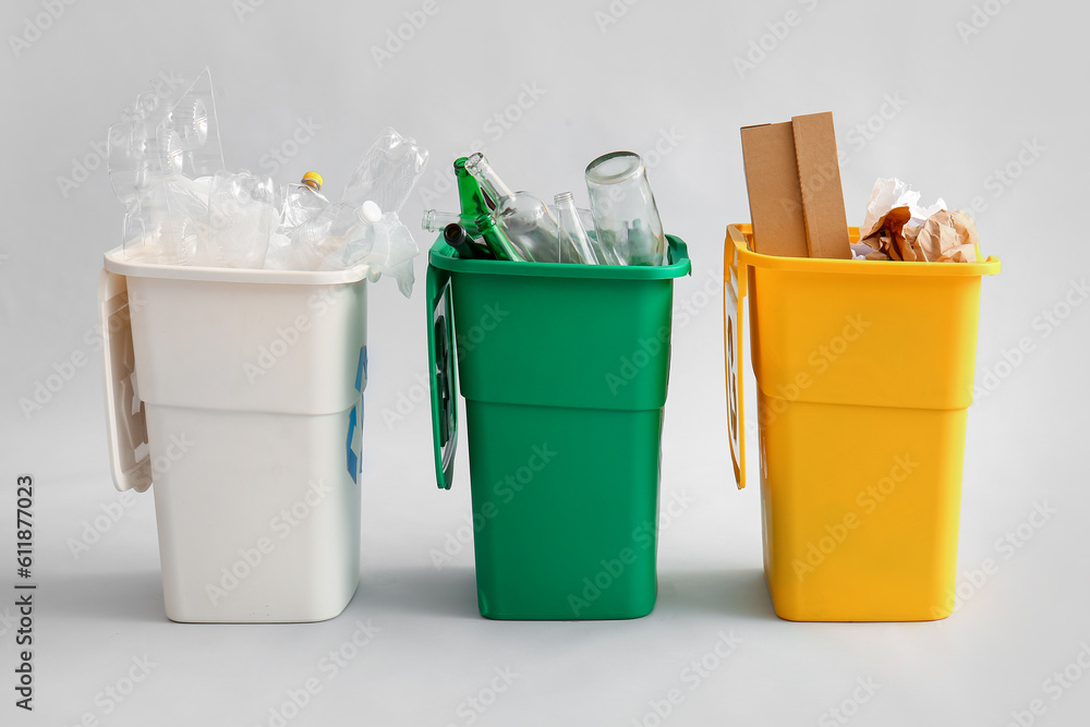 Containers with different types of garbage on light background. Recycling concept