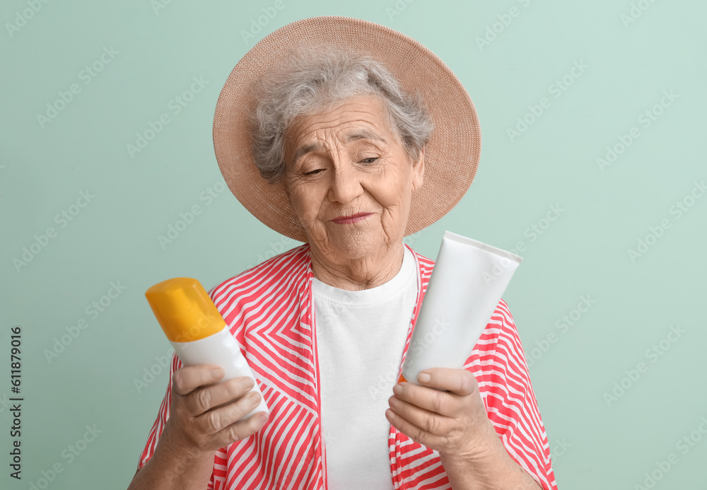 Senior woman with sunscreen cream on green background, closeup