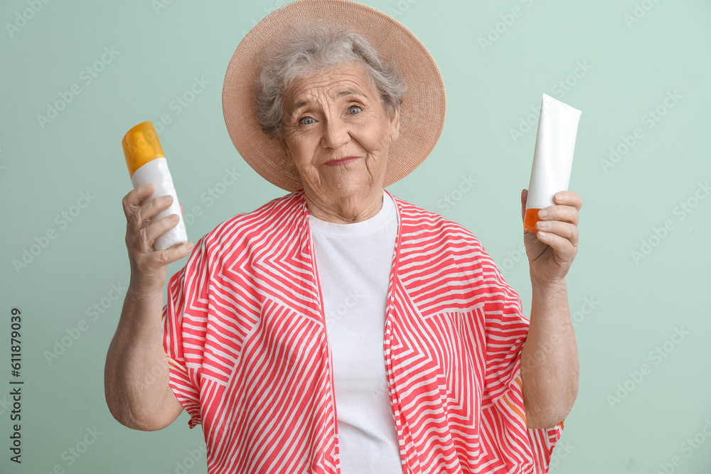 Senior woman with sunscreen cream on green background